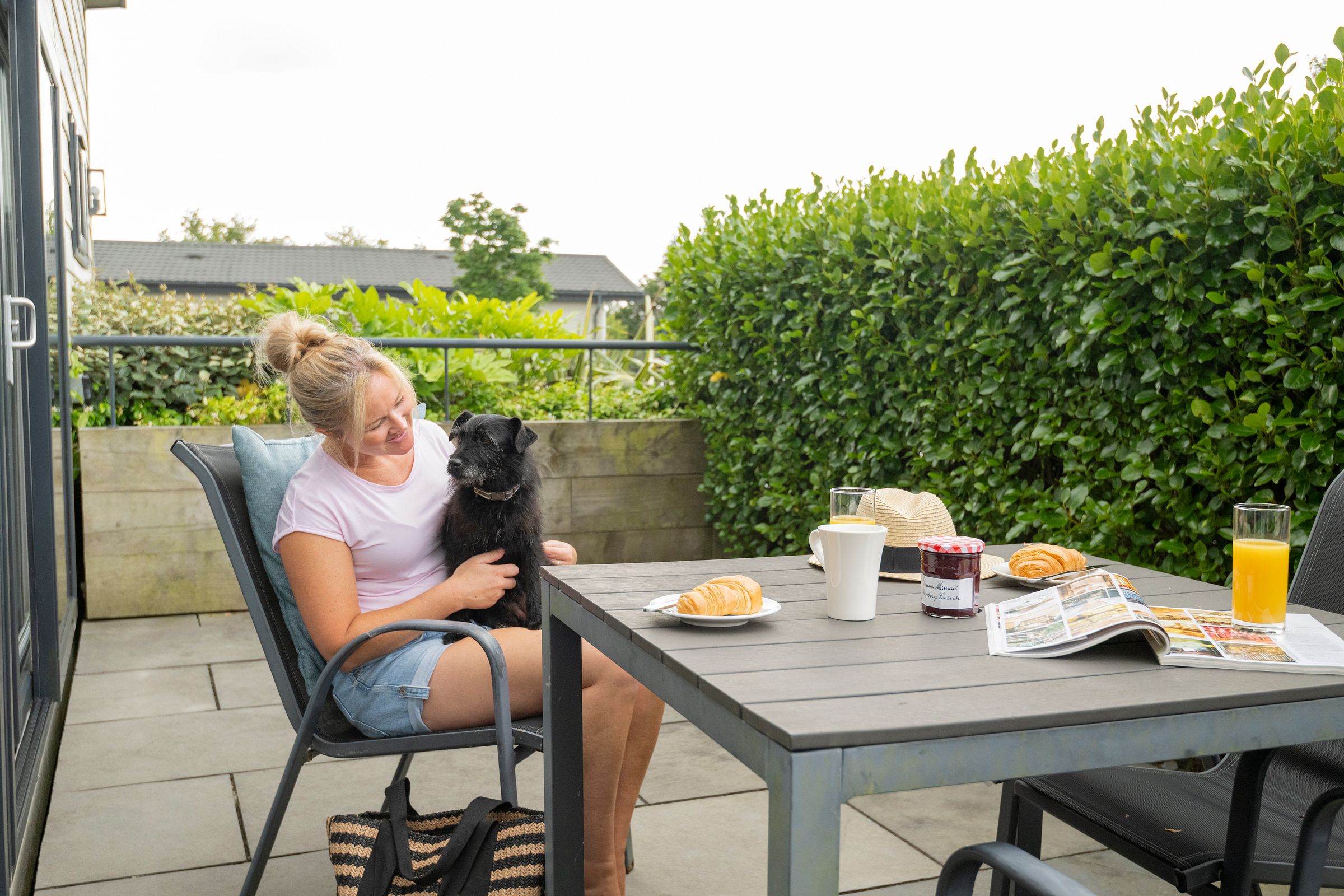 Decking with woman and dog eating breakfast